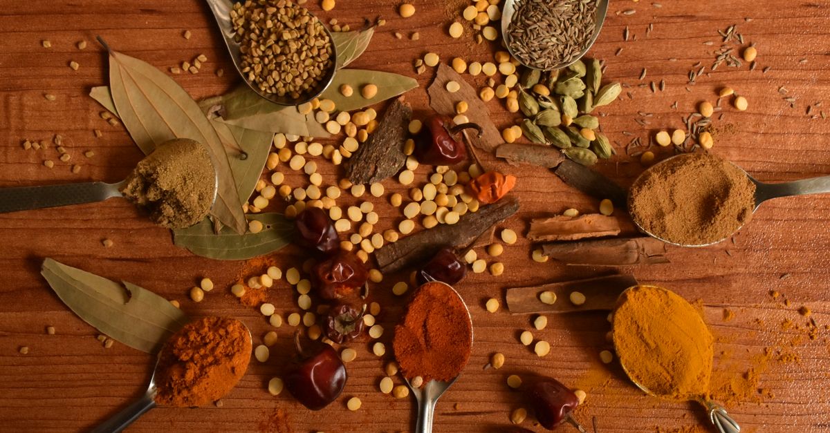 A vibrant display of various Indian spices arranged creatively on a wooden table.