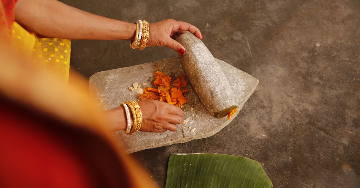 Close-up of turmeric grinding for a South Asian wedding ritual, highlighting cultural heritage.
